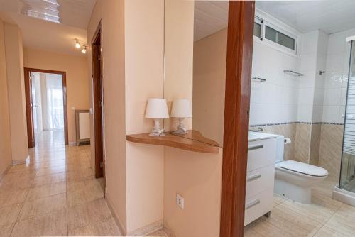 ein Badezimmer mit WC und zwei Lampen auf einer Theke in der Unterkunft Apartaments Costamar Calafell in Calafell