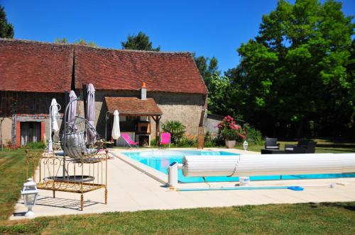 a swimming pool with umbrellas next to a house at LES GUENINS in Gien