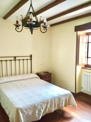 a bedroom with a bed and a chandelier at Casa Fonso in Villapedre