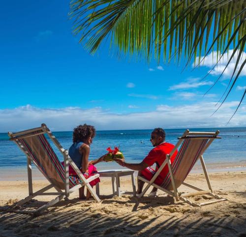 a man and woman sitting in chairs on the beach at Hotel ECOLODGE LE RAVORAHA in Sainte Marie