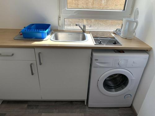 eine Küche mit einer Spüle und einer Waschmaschine in der Unterkunft Großes, modernes Apartment im Souterrain in Frensdorf