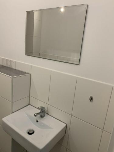 ein weißes Badezimmer mit einem Waschbecken und einem Spiegel in der Unterkunft Großes, modernes Apartment im Souterrain in Frensdorf