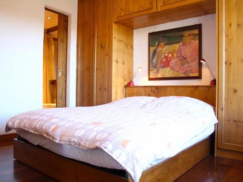 ein Schlafzimmer mit einem Bett mit einem Bild an der Wand in der Unterkunft Central & Spacious | Ambassadeurs A in Crans-Montana