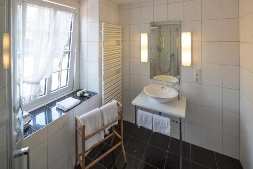 een witte badkamer met een wastafel en een spiegel bij Hotel Haus Recke in Balve