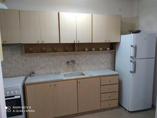 a kitchen with a white refrigerator and wooden cabinets at Mary's apartments in Kiáton