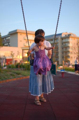 a little girl in a dress sitting on a swing at Panorama Apartman in Velence