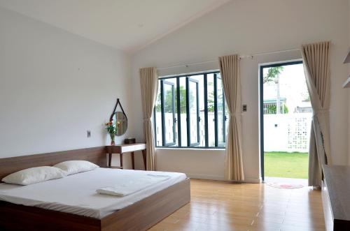 een slaapkamer met een bed en een groot raam bij Villa Kim Yến Lagi in La Gi