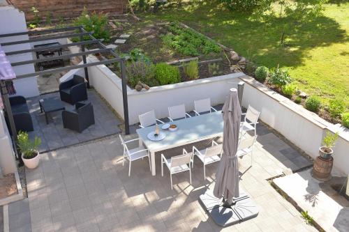 a patio with a table and chairs and an umbrella at Maison D'hôtes Du Landersbach in Sondernach