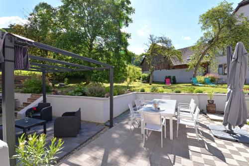 a patio with a table and chairs and an umbrella at Maison D'hôtes Du Landersbach in Sondernach