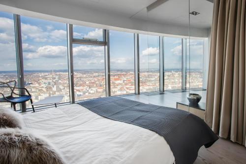 a bedroom with a bed with a view of a city at 30th+ Floor Apartments in Sky Tower in Wrocław