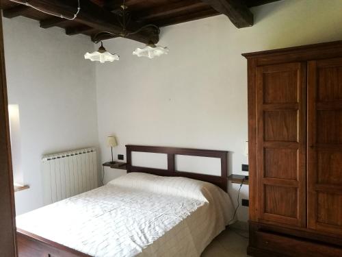 een slaapkamer met een wit bed en een houten kast bij Appto Camelia 1 Bedroom, Living Room, 4 Pax,60mq in Monte Molino
