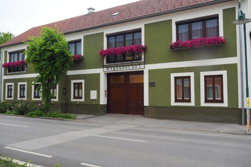 a green and white building with flowers in window boxes at Weghuberhof Ferienwohnungen in Biedermannsdorf
