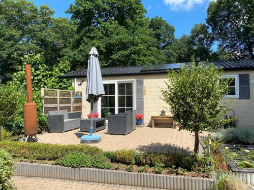a patio with an umbrella and a house at Vakantiehuis Veluwe Wageningen in Wageningen