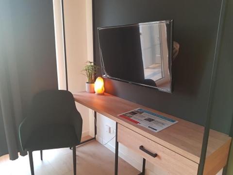 Habitación con escritorio, TV y silla. en Apartament Atram Minimax, en Wroclaw