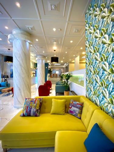 a yellow couch in a lobby with a wall at Paloma Blanca in Dassia