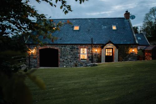 a stone house with christmas lights on a lawn at Bay Tree Cottage in Hillsborough