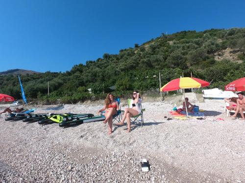 a group of people sitting on a beach at Camping Jungle in Borsh in Borsh