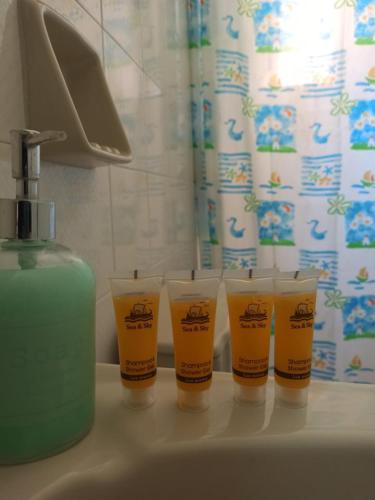 four cups sitting on a bathroom sink next to a bottle of soap at Corfu Sunflower Apartments in Benitses