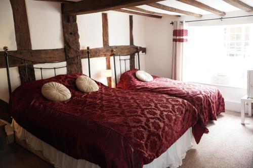 a bedroom with two beds with red comforters and a window at The Poppy House in Bishops Castle