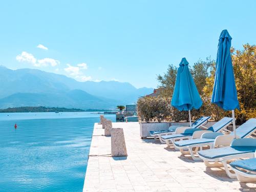 a row of chairs and umbrellas next to the water at Apartments Maestral in Tivat