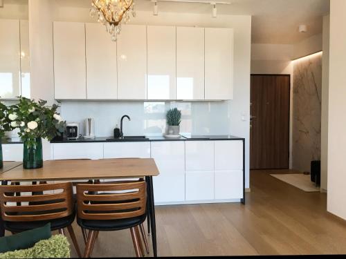 a kitchen with white cabinets and a wooden table at Green Apartment Gdańsk z GARAŻEM in Gdańsk