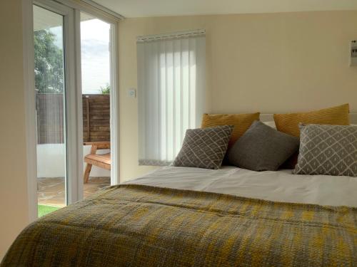 Un dormitorio con una cama grande con almohadas. en Cosy Cabin for two with country side views en Churchstow