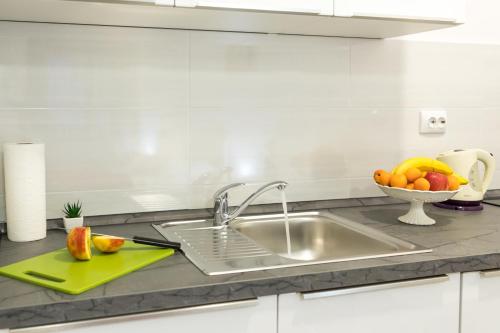 a kitchen counter with a sink and a bowl of fruit at Apartments Santa Maria in Dubrovnik