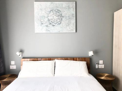 a bedroom with a bed with white sheets and a painting on the wall at Apartments by Sliema promenade and beach in Sliema