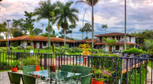 a patio with a table and chairs in front of a house at Hotel Campestre Los Nogales in Quimbaya