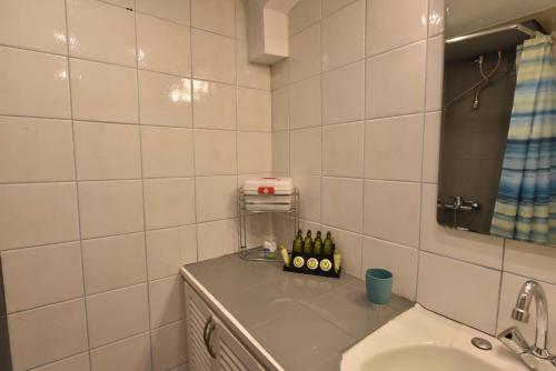 a white tiled bathroom with a sink and a mirror at jasmine apartments in Eretria