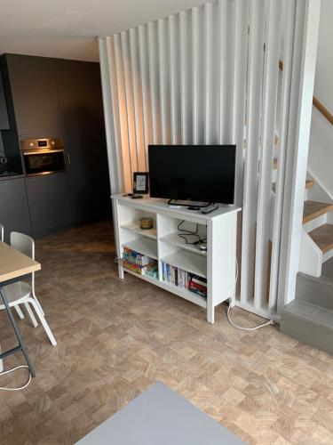 a living room with a television on a white cabinet at TERRASSES DE MALMEDY Triplex 259 " C EST LA VIE " in Malmedy