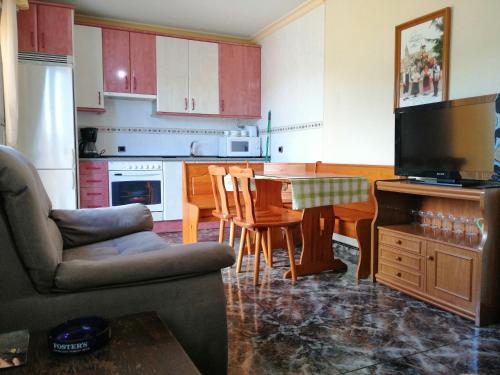 cocina con sofá y mesa con TV en Casa Rural Amelia, en Cepeda