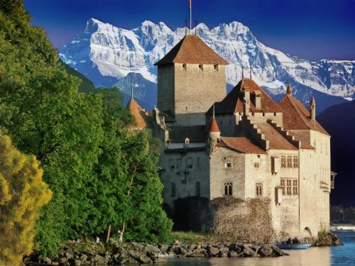 a castle on the shore of a river with mountains in the background at Appartement Le 18 in Ependes