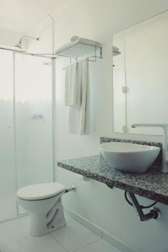 a white bathroom with a sink and a toilet at Hotel Solaris in São Miguel dʼOeste