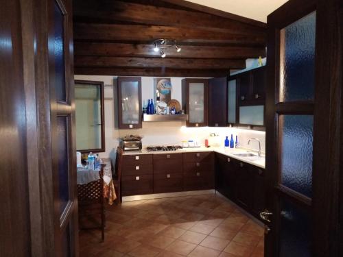 a kitchen with dark wood cabinets and a sink at Brezza di mare appartamento in Villa con giardino e spiaggia ,casa vacanze al mare in Quartu SantʼElena
