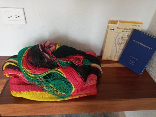 una manta colorida sentada en un estante de madera junto a un libro en La Aldea Zipolite en Zipolite