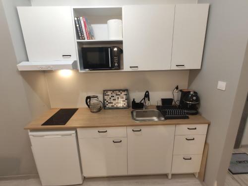 a kitchen with white cabinets and a sink and a microwave at Apartament Olsztyn Twoja Przestrzeń in Olsztyn