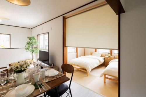 ANJIN STAY AWAJI - Vacation STAY 83766 في Awaji: غرفة معيشة بها سريرين وطاولة طعام
