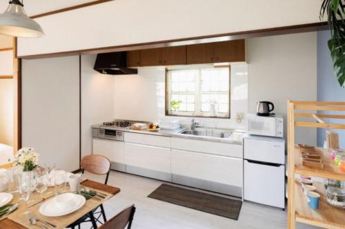 eine Küche mit weißen Schränken und einem Esstisch in der Unterkunft ANJIN STAY AWAJI - Vacation STAY 83766 in Awaji
