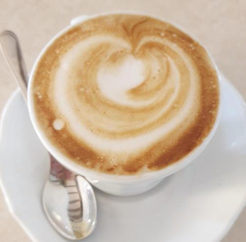 a cup of coffee on a white plate with a spoon at Villa Serena Agriturismo in Montebelluna