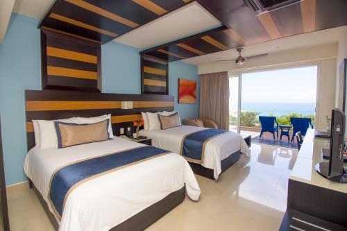 2 camas en una habitación con vistas al océano en Secrets Huatulco Resort & Spa, en Santa Cruz Huatulco