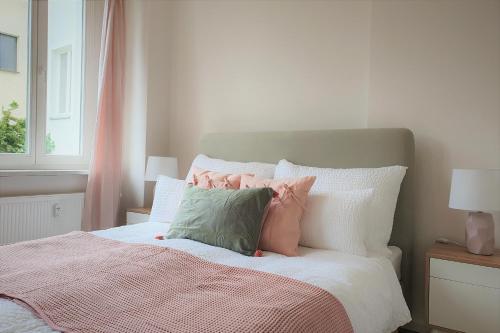ein Bett mit rosa und grünen Kissen darauf in der Unterkunft PB Ferienwohnungen - FeWo 2 - Stilvoll eingerichtetes Apartment im Herzen Senftenbergs in Senftenberg