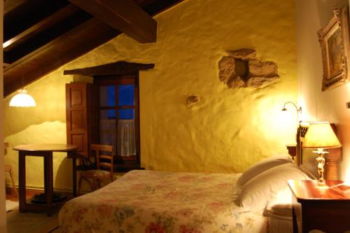 a bedroom with a bed and a table and a window at La Casona de Villanueva de Colombres in Villanueva