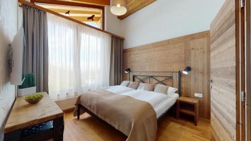 1 dormitorio con 1 cama y pared de madera en Apartmány iziJasná, en Demänovská Dolina