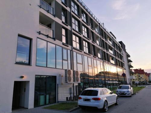 un coche blanco estacionado frente a un edificio en Jurajska Plaza - Nowoczesny apartament z osobną sypialnią, Parking GRATIS - HK Apartaments Kielce en Kielce