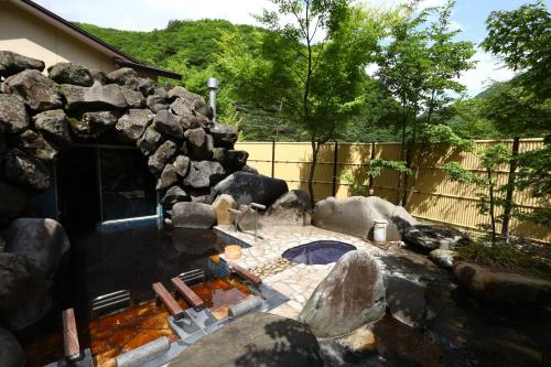 a backyard with a swimming pool and a stone wall at Keiryuso Siorie in Matsumoto