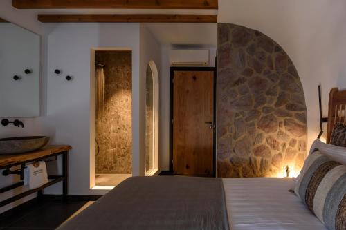 a bedroom with a bed with a stone wall at Vrachos Suites Mykonos in Mýkonos City