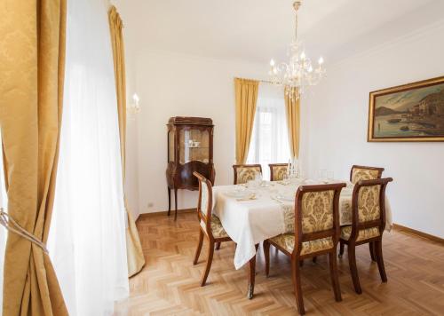 ein Esszimmer mit einem Tisch, Stühlen und einem Kronleuchter in der Unterkunft Suite Sarandrea in Rom