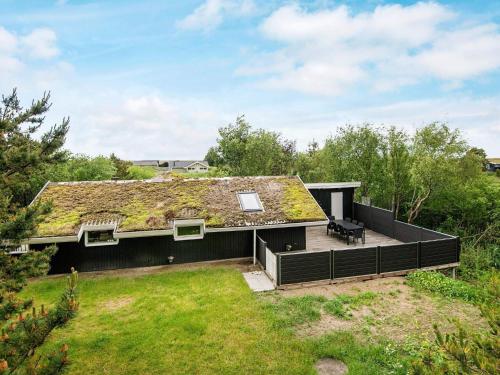 a house with a grass roof with a deck at 6 person holiday home in R m in Bolilmark