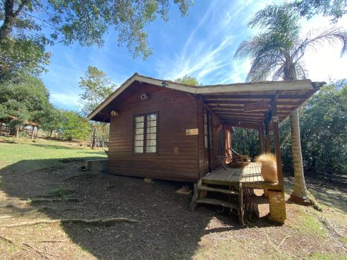 een kleine houten hut met een veranda en een boom bij Pousada Aguaraguazu in Tibagi